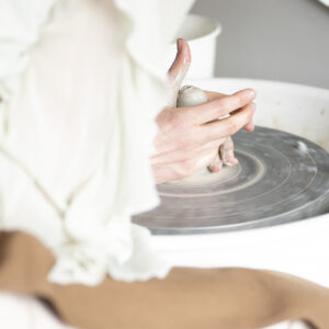 A detailed, tactile perspective through a mirror, capturing the precise and intuitive movement of hands molding a ceramic vessel