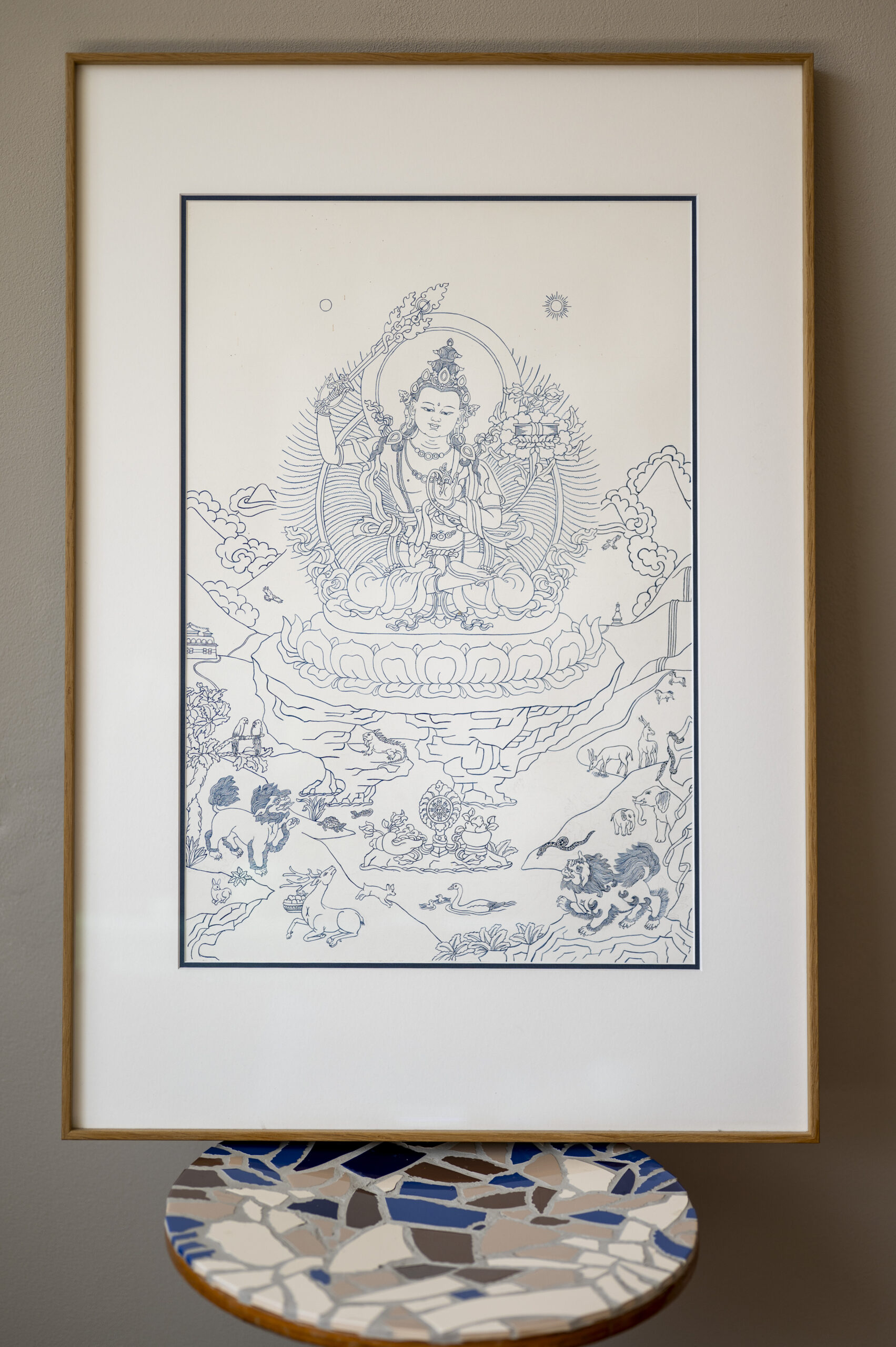 A framed sacred Thangka artwork of Manjushri displayed on a cherished mosaic chair from the artist's grandfather inside the Artelier