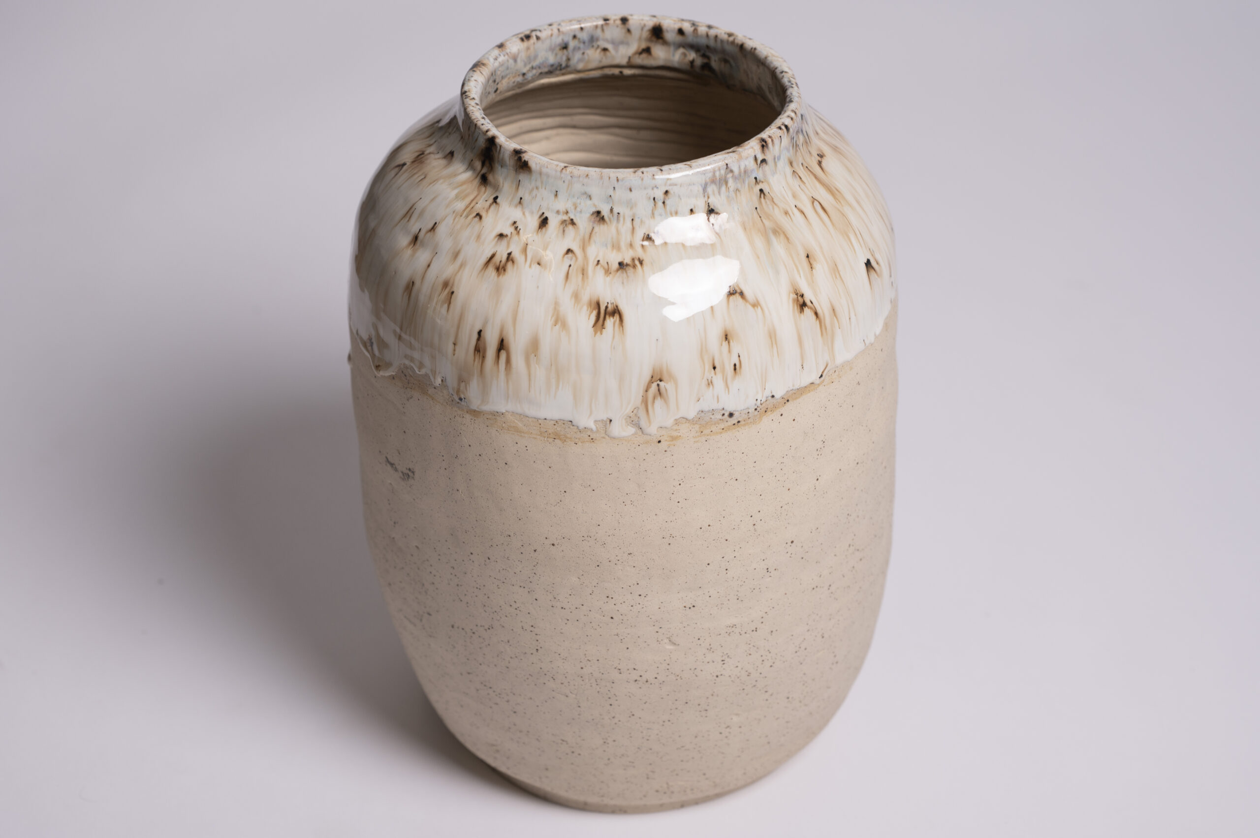 A large archival ceramic vase, showcasing a beautiful glossy white glaze with rustic brown speckles on its surface 4