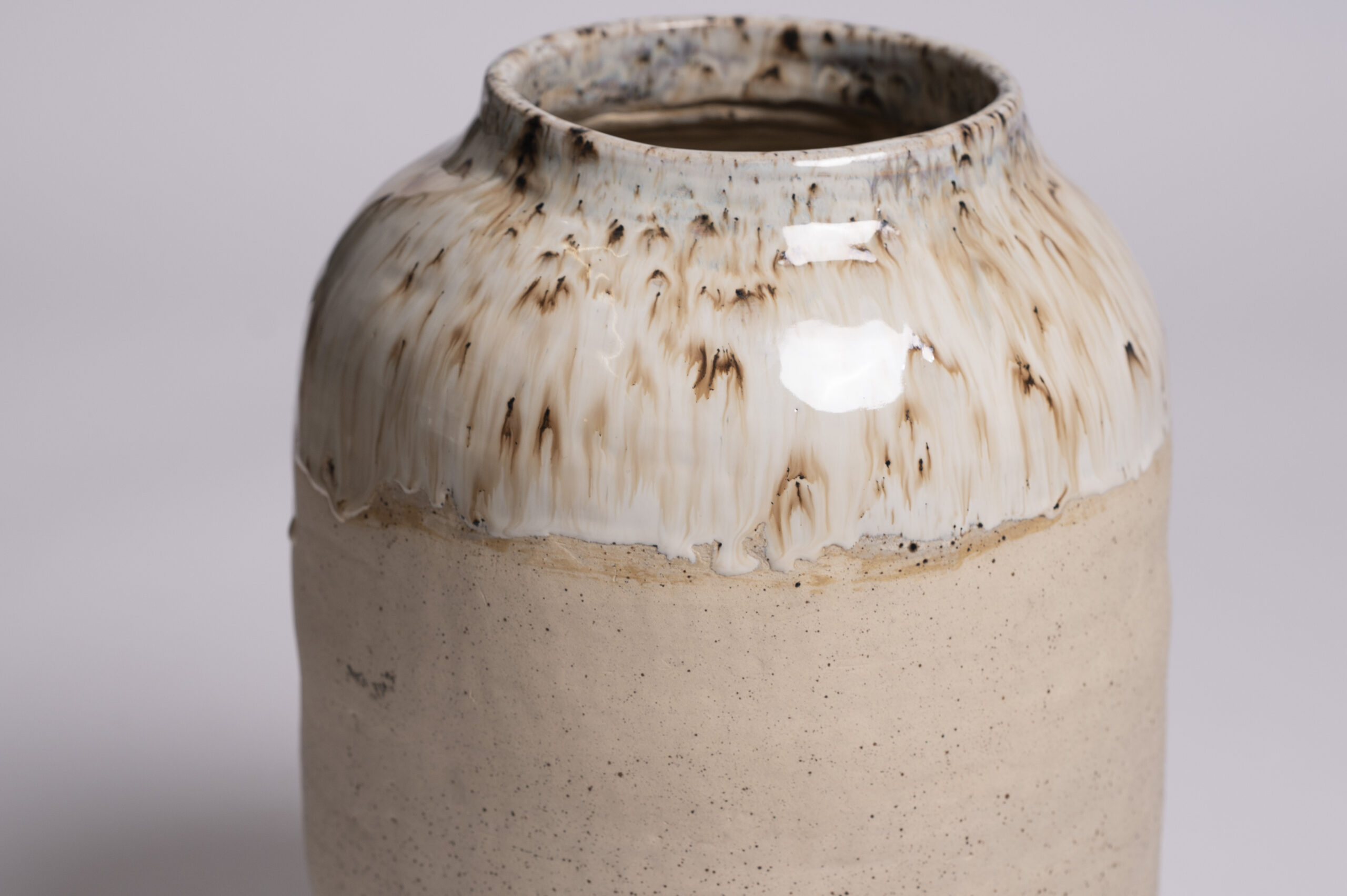 A large archival ceramic vase, showcasing a beautiful glossy white glaze with rustic brown speckles on its surface 2